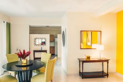 Round dining table with yellow chairs by a console table under a mirror in Executive Suite at Hotel Montana Haiti