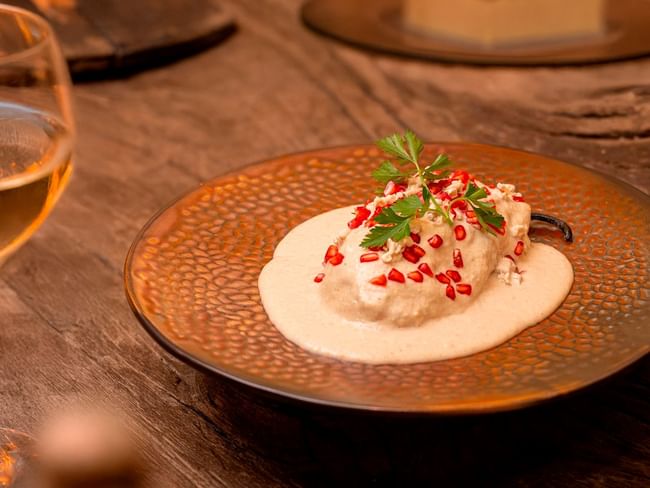 Stuffed poblano pepper topped with walnut sauce, pomegranate seeds, and parsley served with white wine.