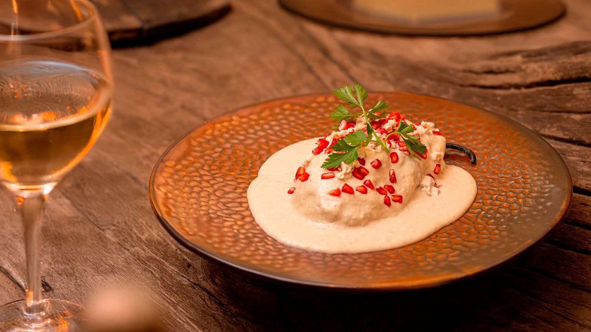 Stuffed poblano pepper topped with walnut sauce, pomegranate seeds, and parsley served with white wine.