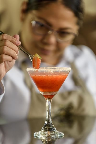 Chef holds a strawberry over a drink at Diez Hotel Categoría