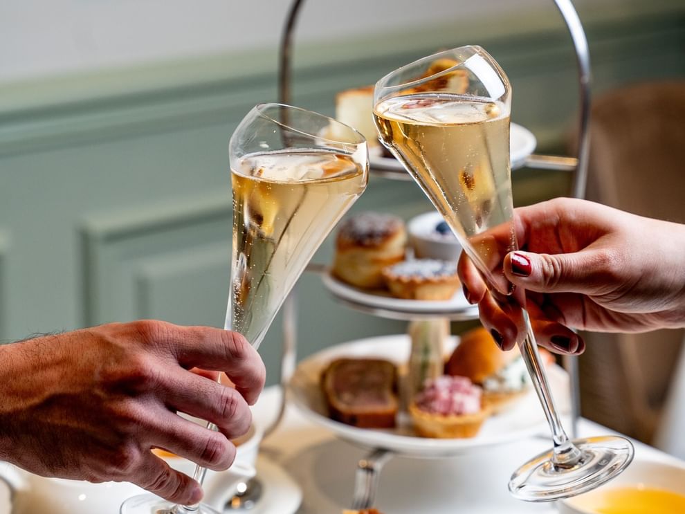 Deux personnes trinquant avec des coupes de champagne lors d'un goûter à l'Hôtel Westminster, à Paris.