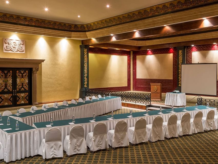 Salón San Marcos featuring a podium, projector screen, and patterned rug at Quinta Real Aguascalientes