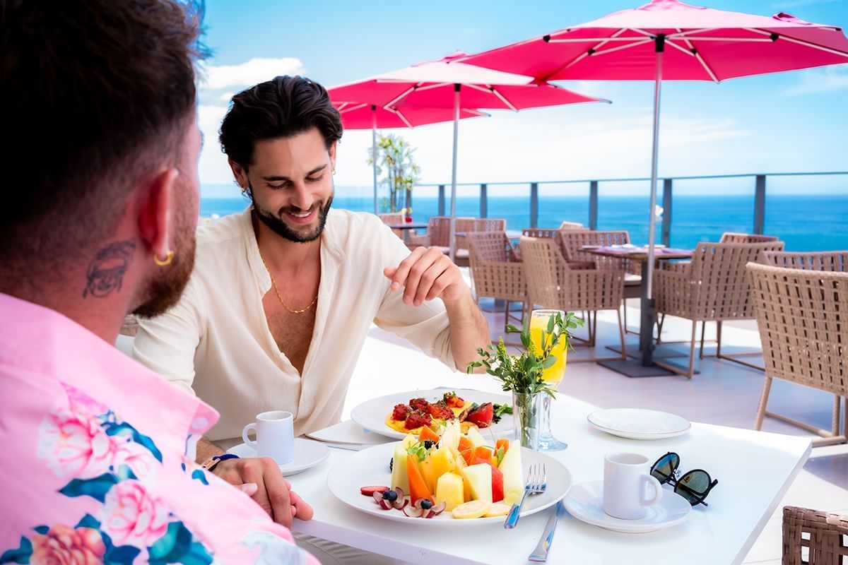 Two men enjoying breakfast meal in The Top Sky Bar with an ocean view at Almar Beach Resort