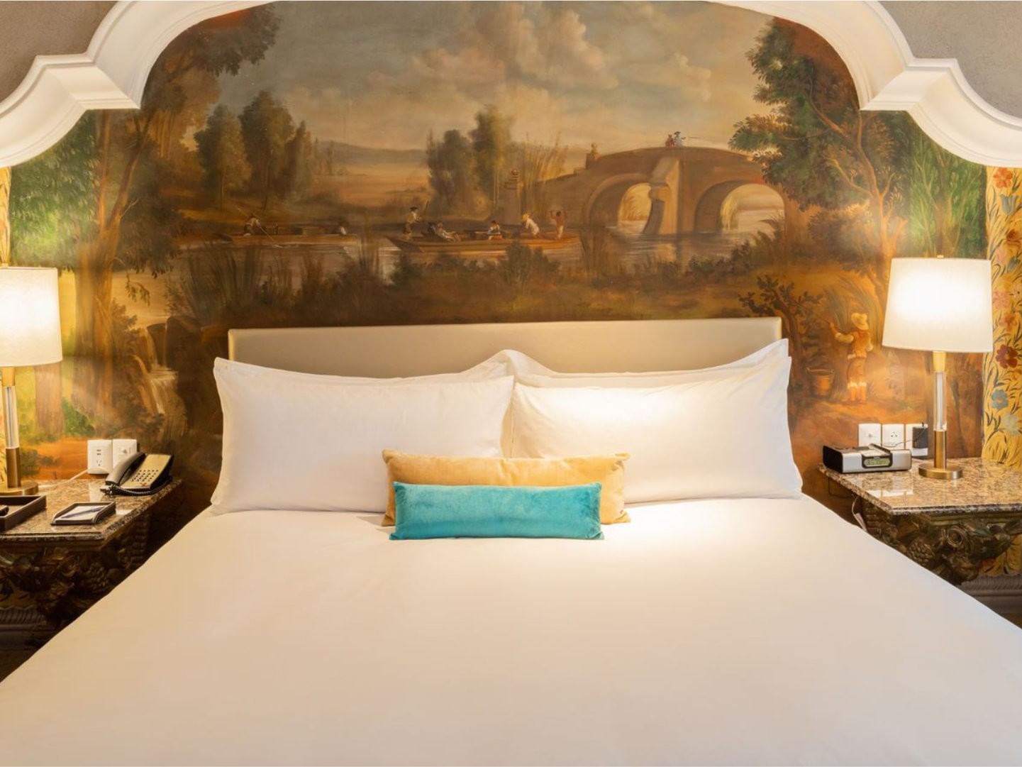 Stunning hand-painted mural headboard behind a plush bed in King Executive Tower at Quinta Real Monterrey