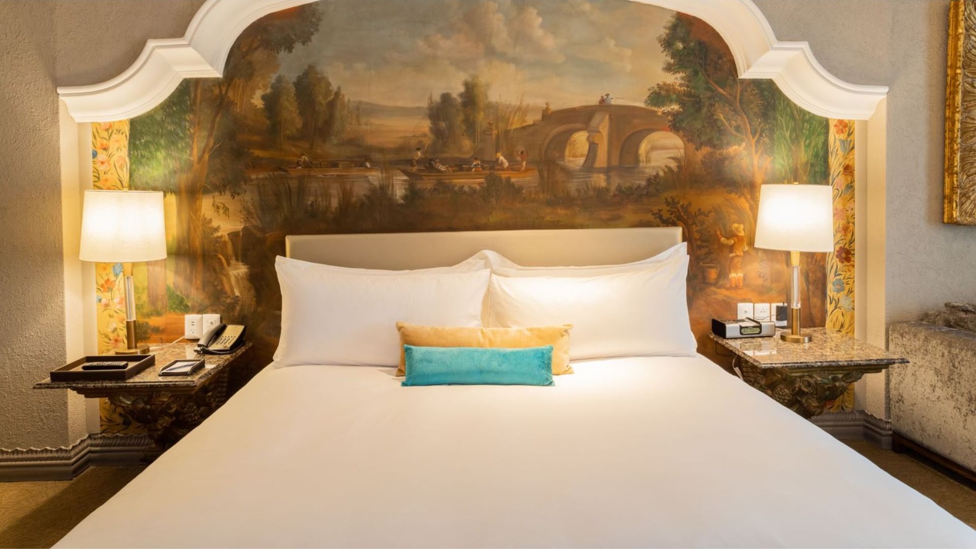 Stunning hand-painted mural headboard behind a plush bed in King Executive Tower at Quinta Real Monterrey