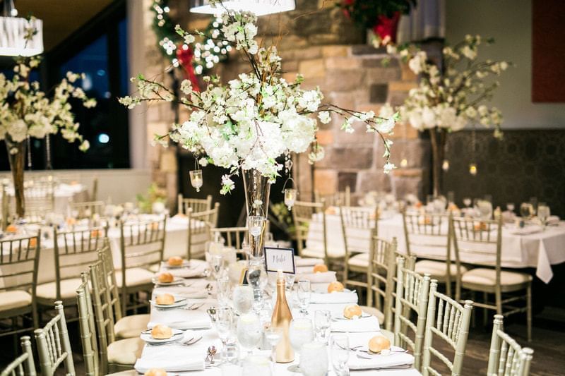 Elegant banquet hall with white linens, gold chiavari chairs, and floral centerpieces at Aramark Chauncey Conference Center