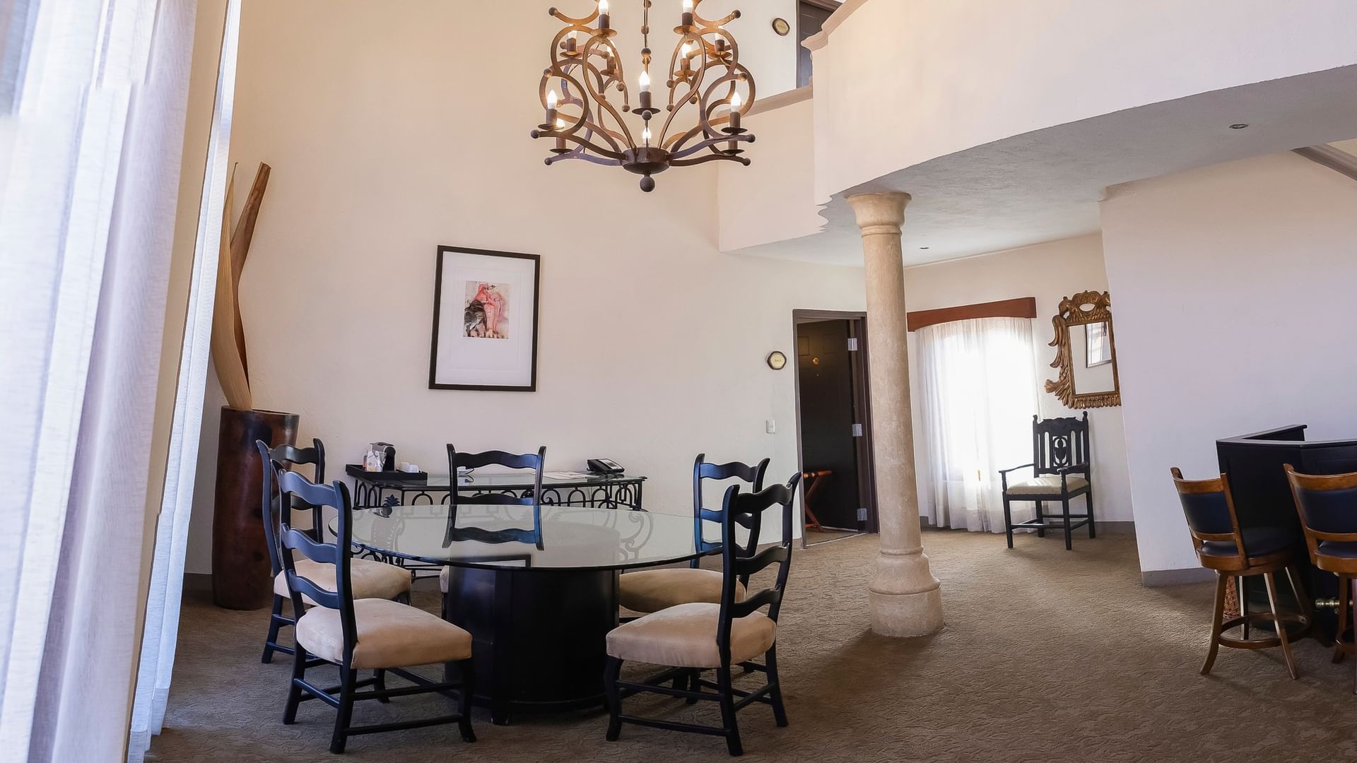 Spacious King Presidential Suite dining area with round table, ornate chandelier, and stone column at Quinta Real Zacatecas
