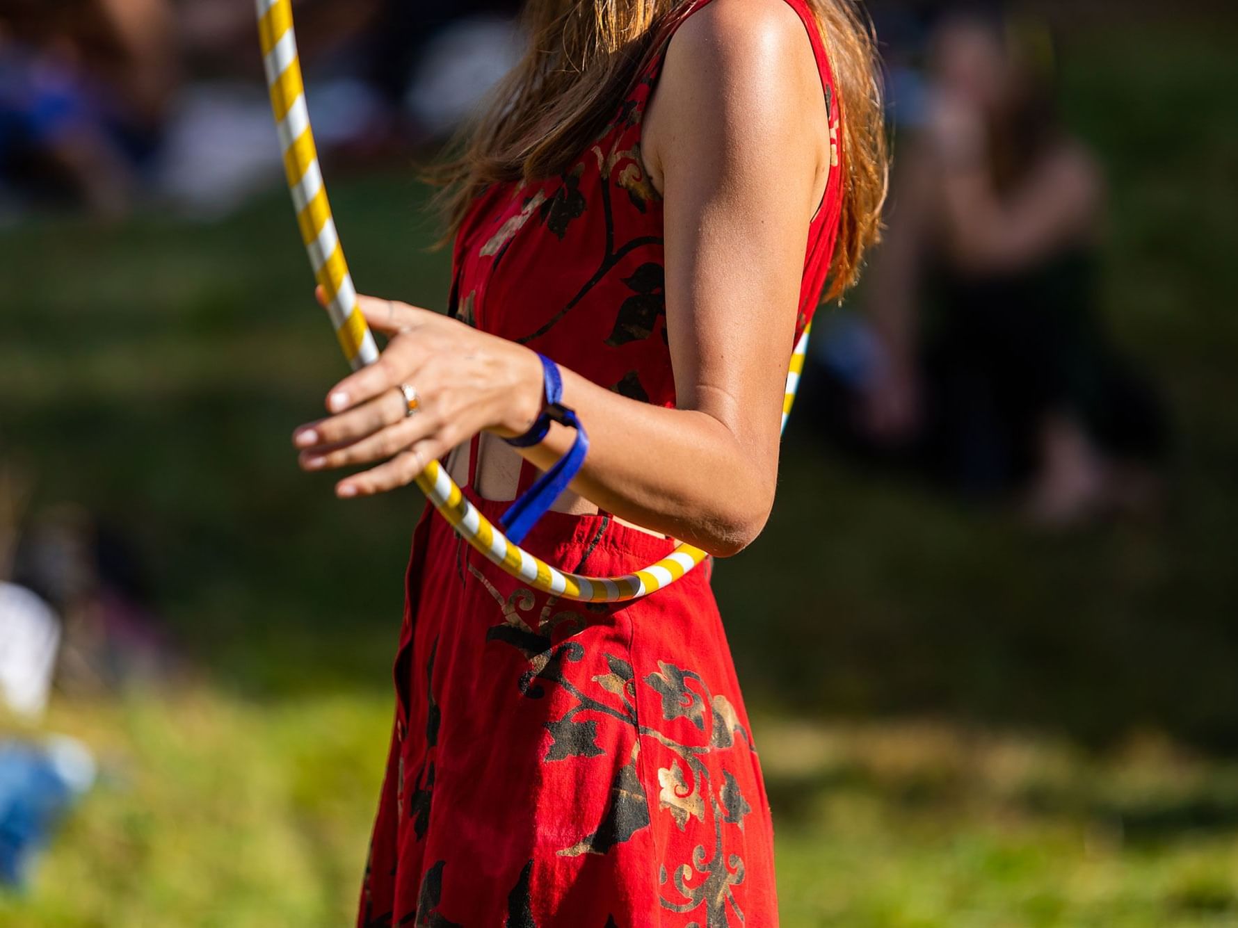 Woman in a red dress holding a yellow and white hula hoop with blue wristbands near High Peaks Resort