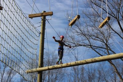 Person walking on log in the air at a ropes course