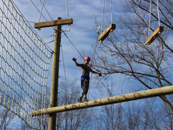Person walking on log in the air at a ropes course