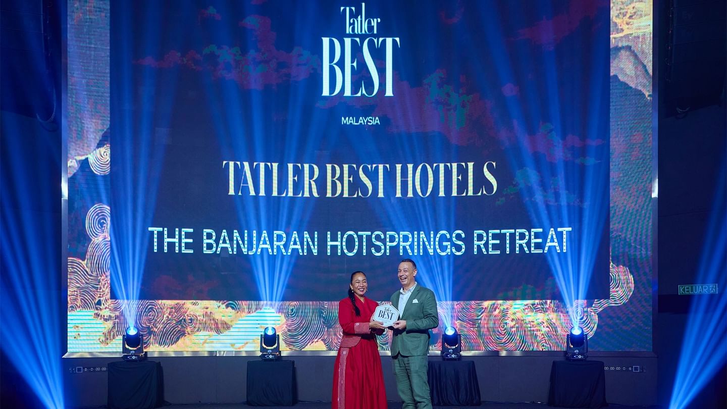 Marc Groh on stage holding an award at the Tatler Best Hotels Malaysia event with blue lighting and digital displays