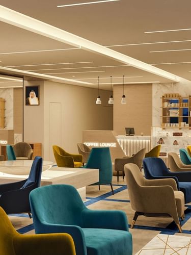 Colorful armchairs by marble tables under a warm glow in The Tower View at Cantonal Hotel by Warwick Riyadh