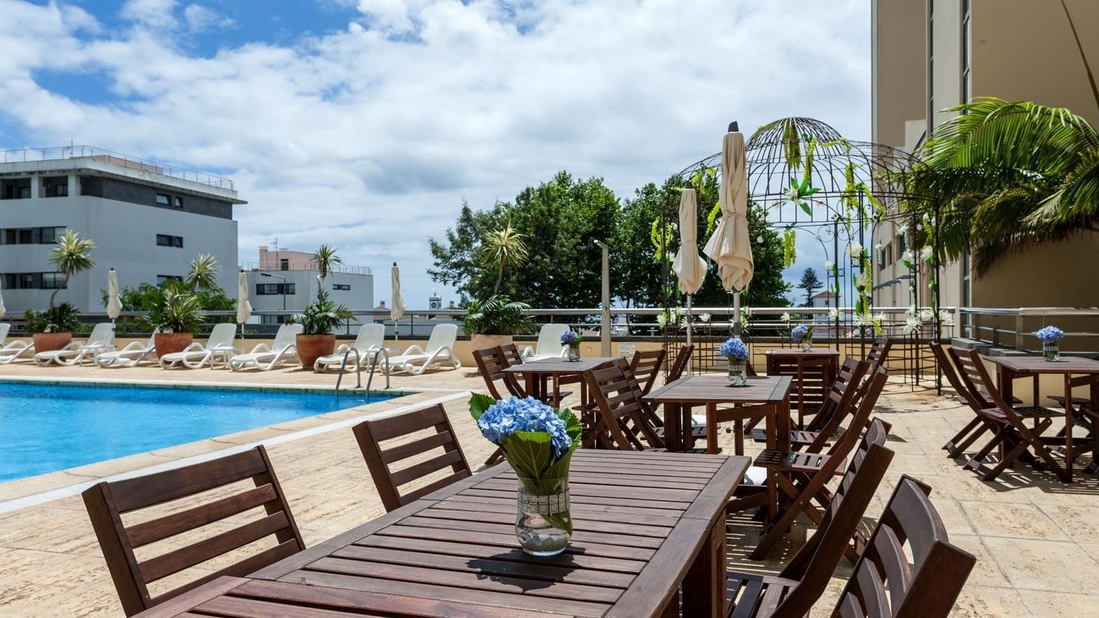Tables by an outdoor pool in  Bar Atlantida at Bensaude Hotels