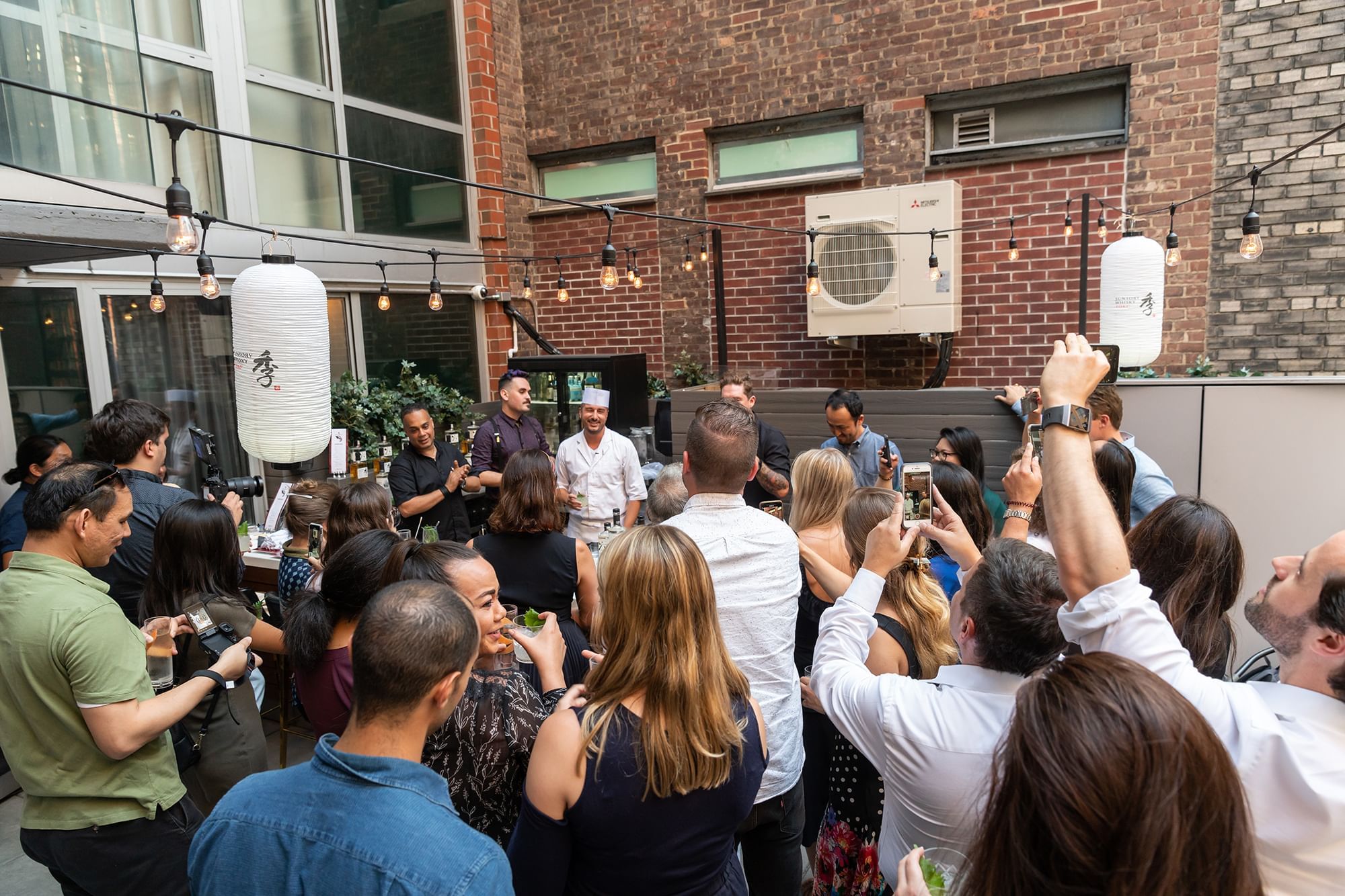 a crowd of people gathered around a table in an outdoor space