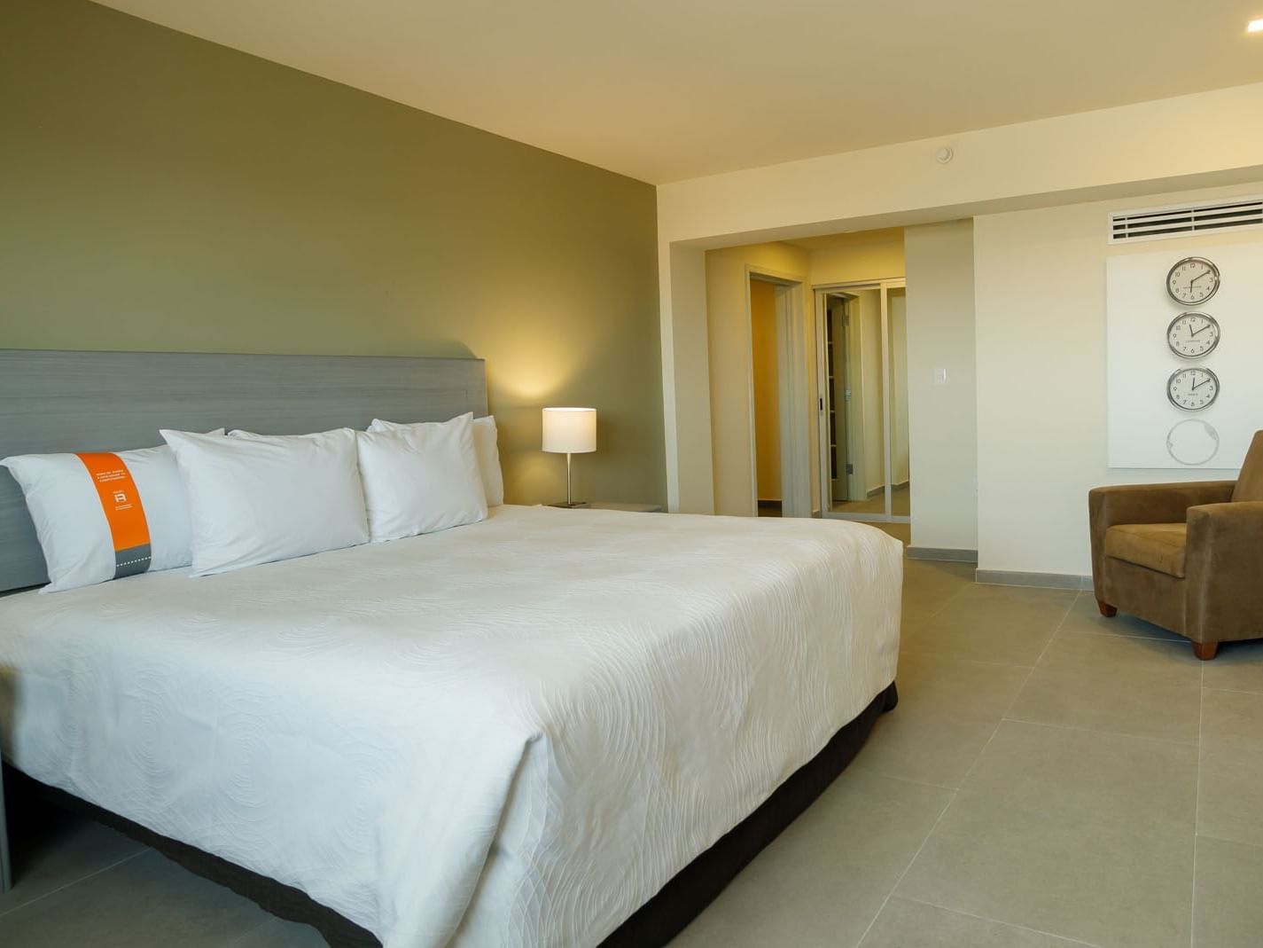 King Master suite showing a king bed and a wall with three decorative world clocks at Real Inn Mexicali