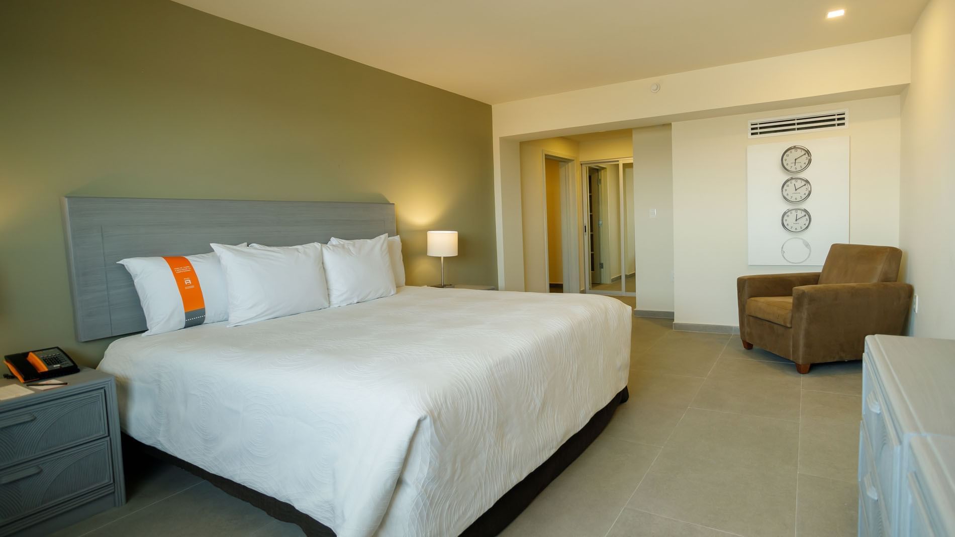 Habitación de hotel con cama grande, silla, mesita de noche y decoración minimalista.