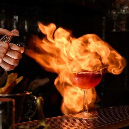 Bartender spraying flammable liquid onto a glass of alcohol - Lexis Suites Penang
