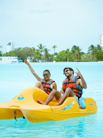 Couple enjoying a yellow paddle boat ride in turquoise waters with palm trees at Playa Blanca Beach Resort