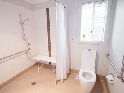 White accessible bathroom with shower, toilet, and grab bars at La Trobe University Regional Housing.