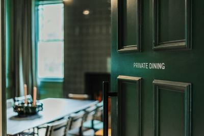Elegant green private dining room door with a blurred interior view at The Stonebreaker Hotel
