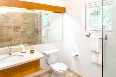 Bright bathroom with stone-tiled shower, vanity sink, and garden-view window at Hotel Montana Haiti