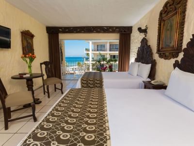 Double room with ornate carved headboards and ocean view balcony at Playa Los Arcos Puerto Vallarta 2023