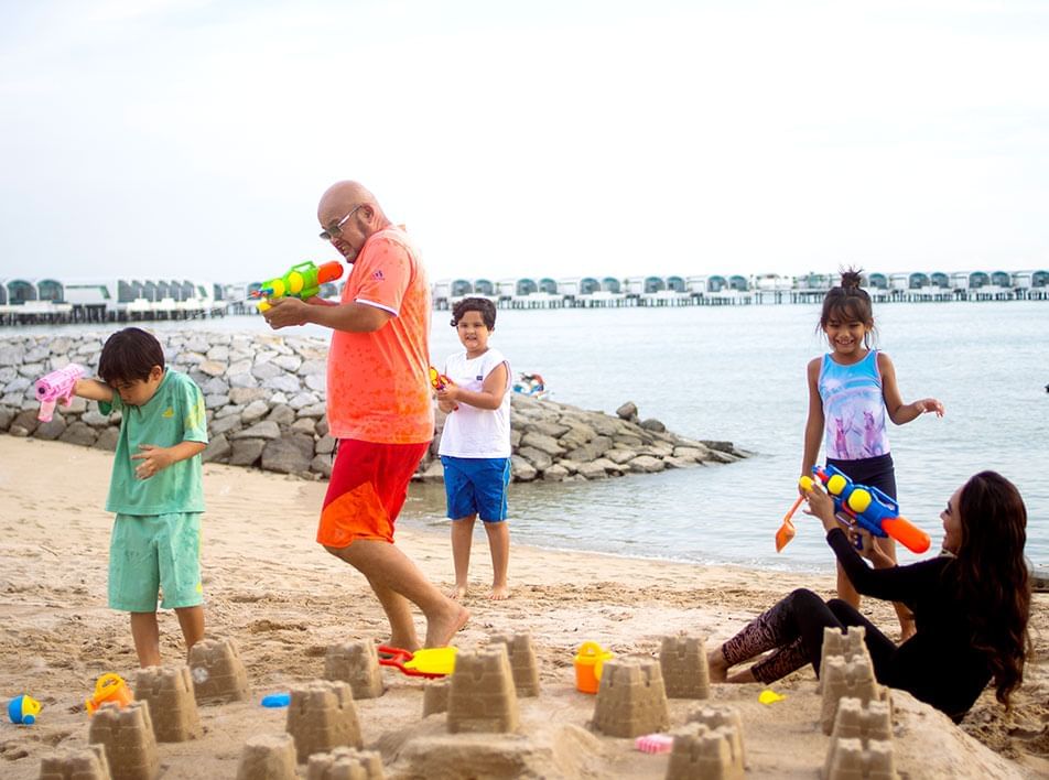 Family members playing water gun on the beach -Lexis Hibiscus