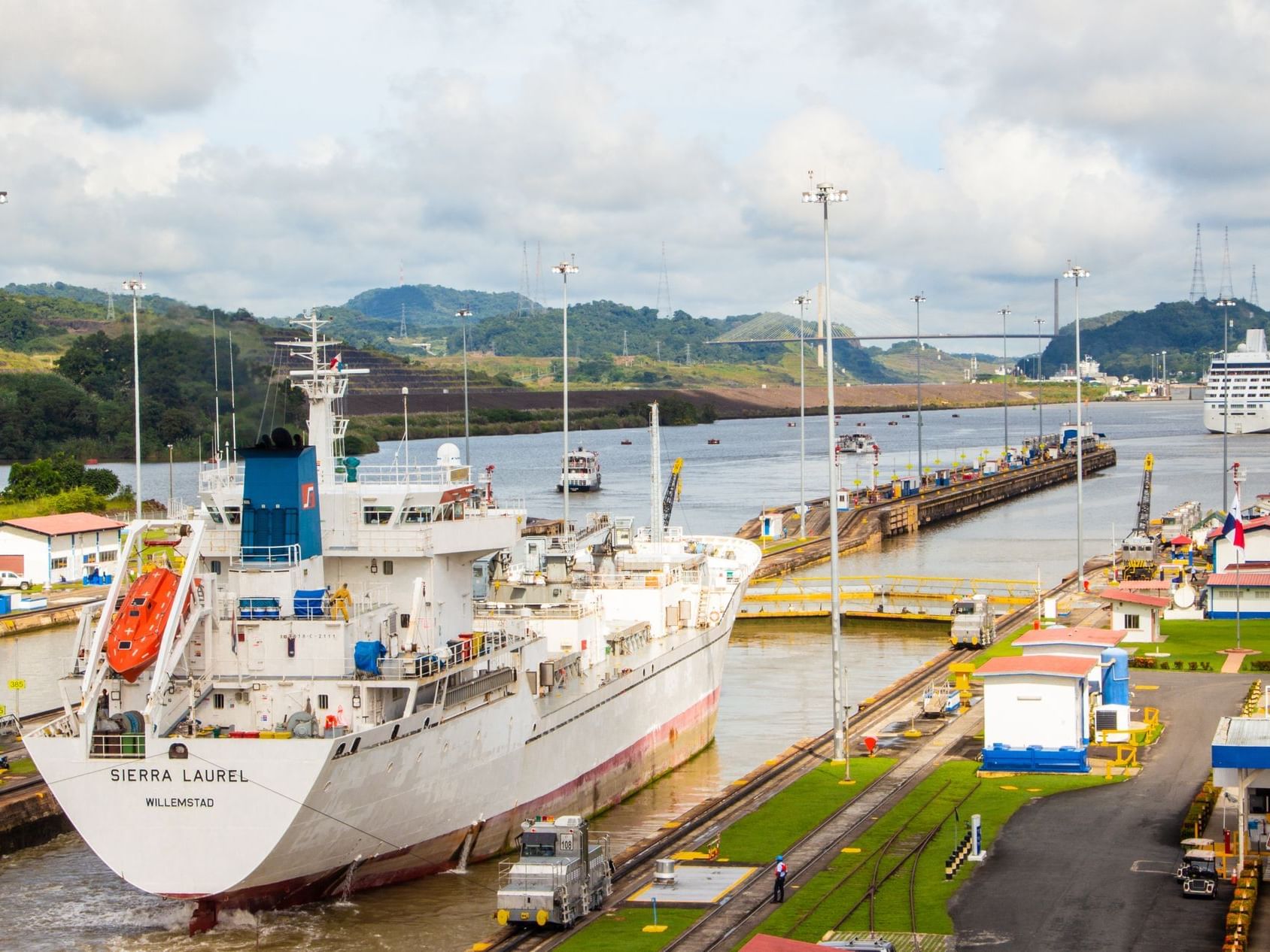 Few boats docked at the Panama Canal and a mountain range at the back