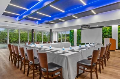 The Riverside Room with a U-shaped table setup facing the projector screen at The J House Greenwich