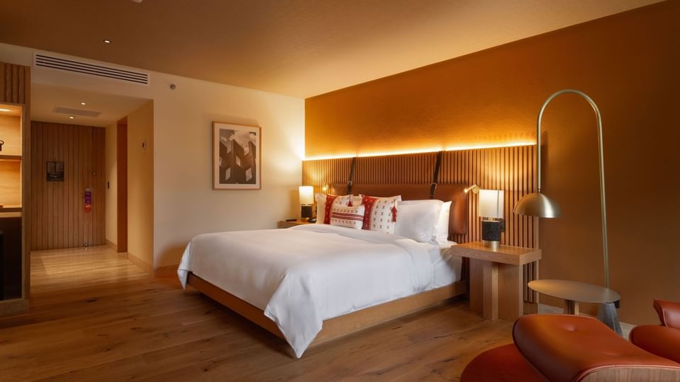 Modern king suite with warm orange accents, wood floors, and sleek designer lighting at Camino Real Polanco Mexico