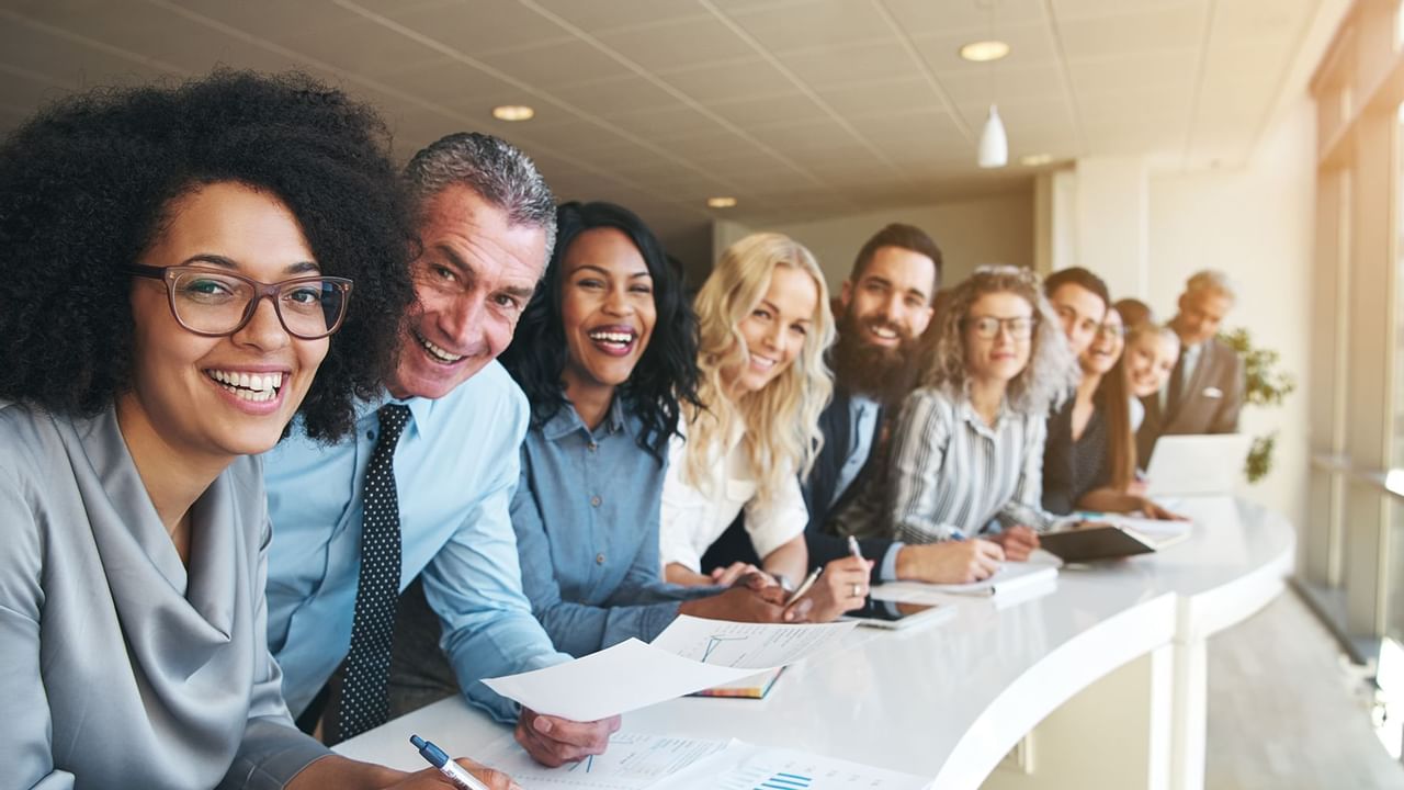 group of people in business clothes leaning over a table smiling