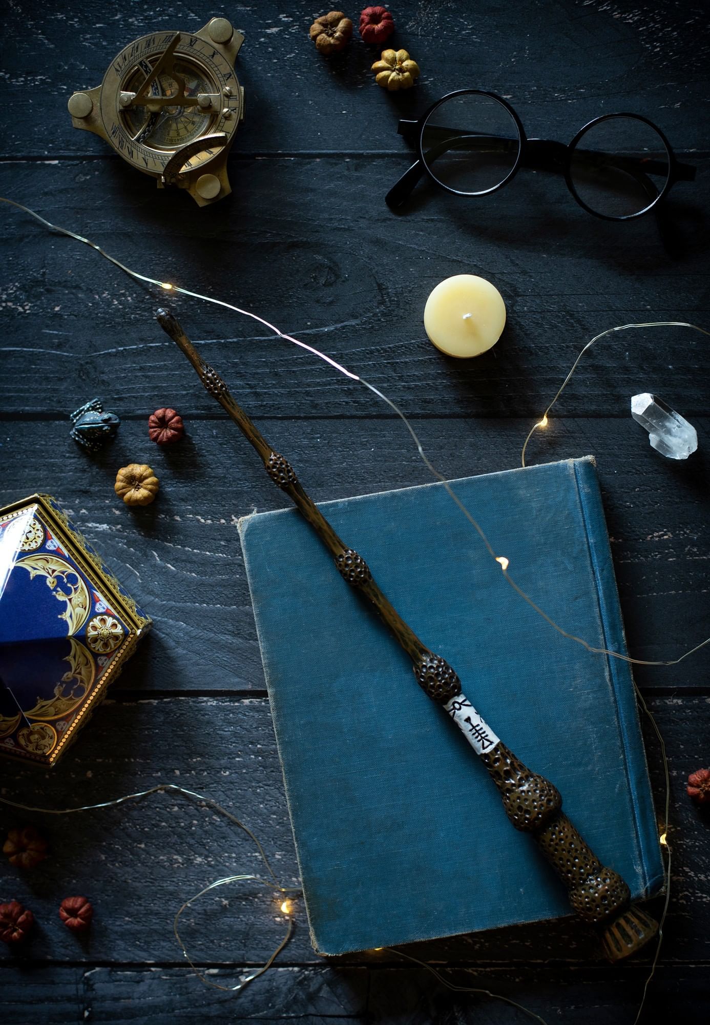 Magic wand placed on a blue book by small pumpkins and a frog figure at The Capital Hotel, Apartments and Townhouse