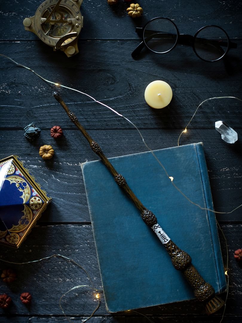 Magic wand placed on a blue book by small pumpkins and a frog figure at The Capital Hotel, Apartments and Townhouse