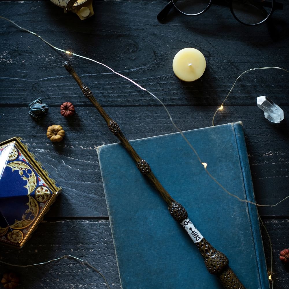 Magic wand placed on a blue book by small pumpkins and a frog figure at The Capital Hotel, Apartments and Townhouse