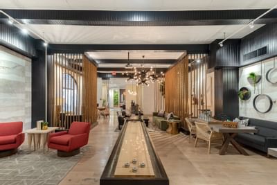 24-Hour Lounge with Games featuring a shuffleboard table, seating, and a lush wall decor at The Riverwalk Plaza Hotel