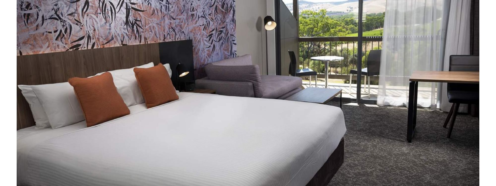 A bright and spacious Accessible Room with a king bed and balcony overlooking a scenic view at Novotel Barossa Valley Resort