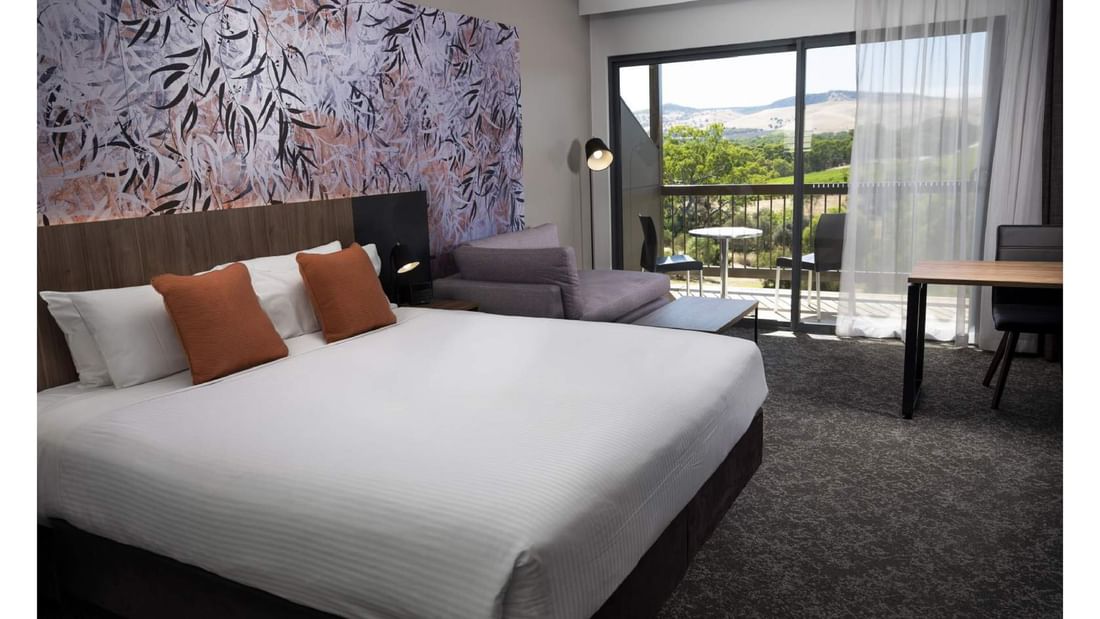 A bright and spacious Accessible Room with a king bed and balcony overlooking a scenic view at Novotel Barossa Valley Resort