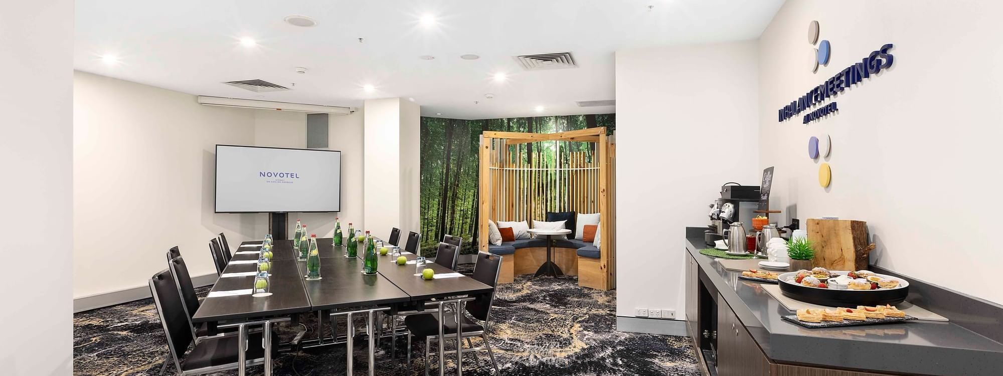Boardroom set-up facing projector screen with refreshment station in The McLaren Room at Novotel Sydney on Darling Harbour