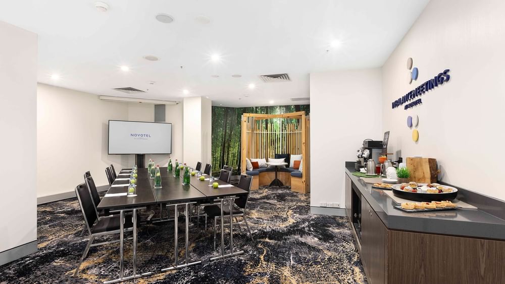 Boardroom set-up facing projector screen with refreshment station in The McLaren Room at Novotel Sydney on Darling Harbour