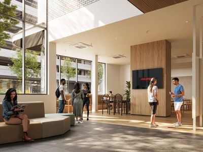 Modern lobby with people, large windows, furniture, and a TV displaying 