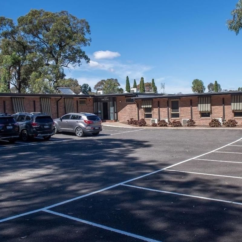 Several cars parked in front of La Trobe University - Orde House building.