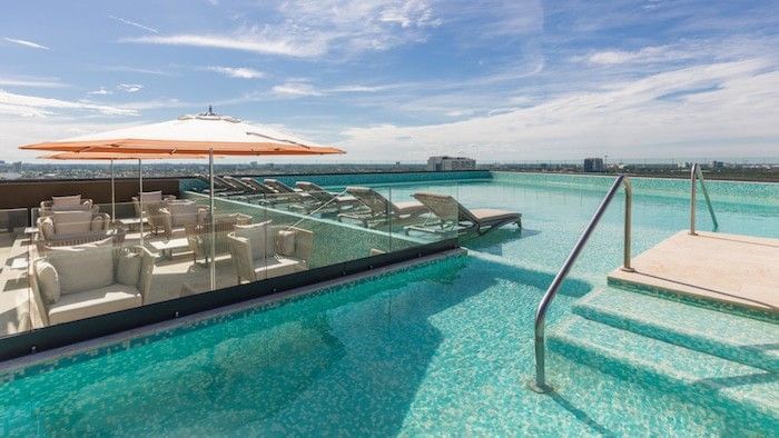 Lounge chairs by an infinity pool under a blue sky surrounding a glass rail at Camino Real Pedregal Mexico