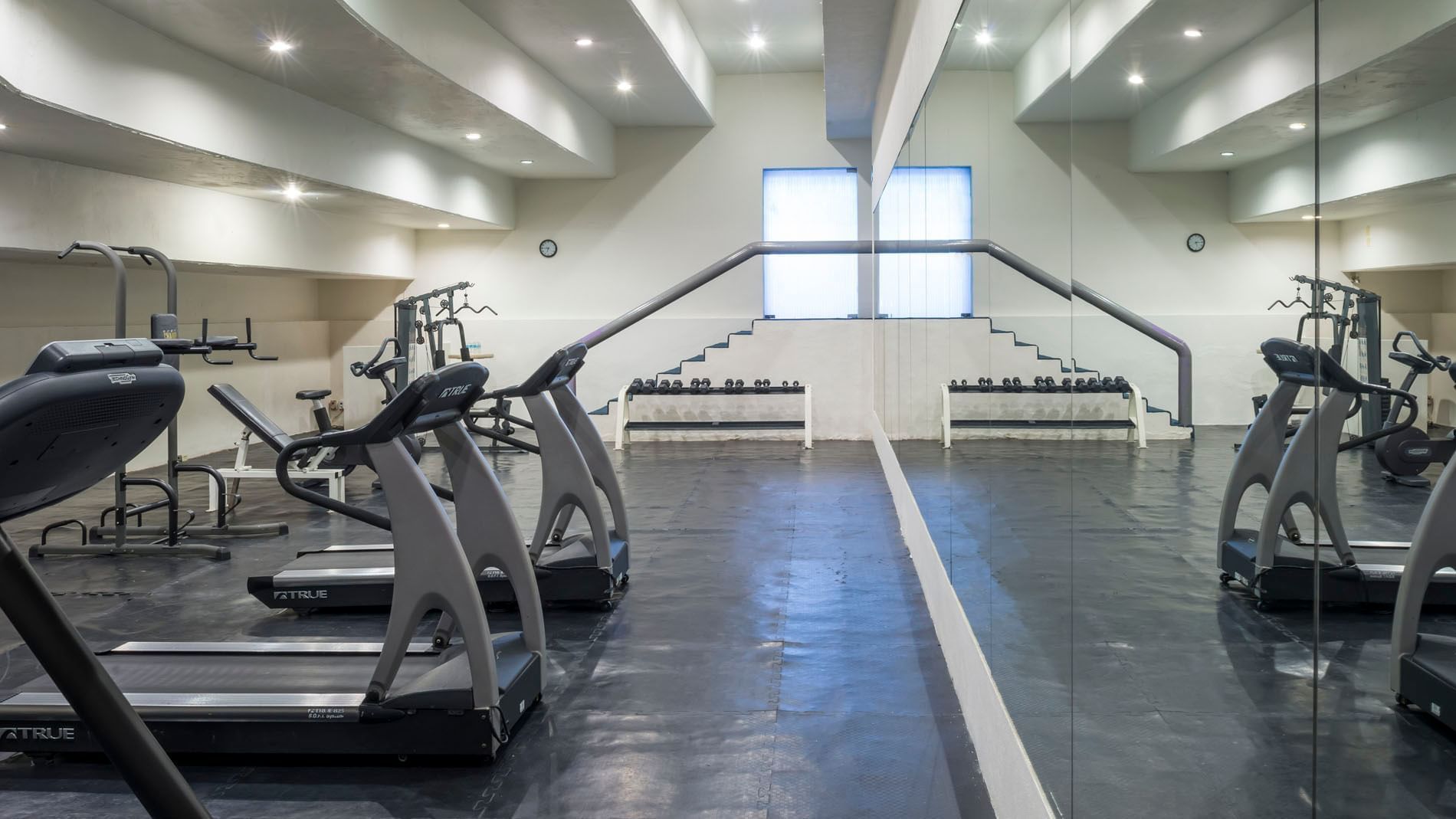 Fitness center at Real Inn Nuevo Laredo, equipped with treadmills, free weights, and floor-to-ceiling mirrors