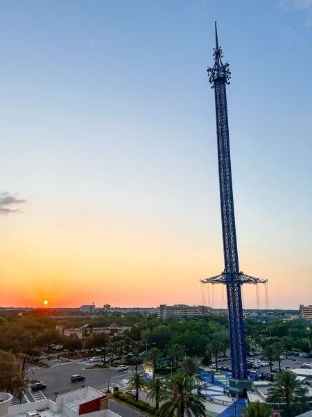 An sky-high view of the Orlando Starflyer ride at ICON Park with a sun setting in the distance.