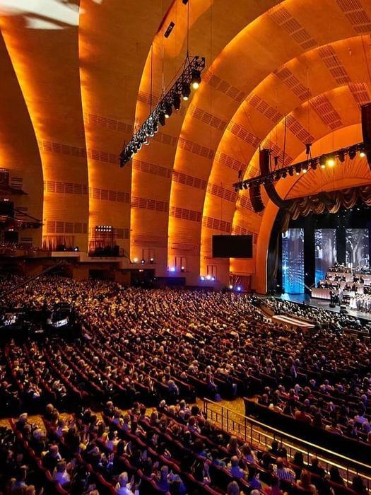 Interior of Radio City Music Hall with rows of plush seats set by a stage near Warwick Hotels & Resorts