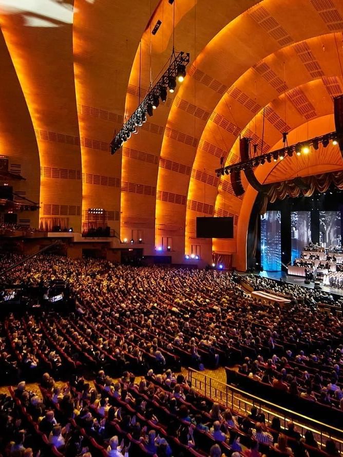 Interior of Radio City Music Hall with rows of plush seats set by a stage near Warwick Hotels & Resorts