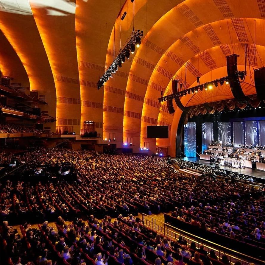 Interior of Radio City Music Hall with rows of plush seats set by a stage near Warwick Hotels & Resorts