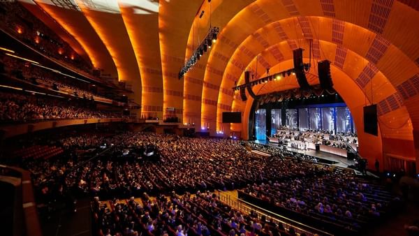 Interior of Radio City Music Hall with rows of plush seats set by a stage near Warwick Hotels & Resorts