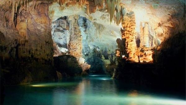 Jeita Grotto, featuring lit rock columns by calm water under stone ceilings near Warwick Palm Beach Hotel