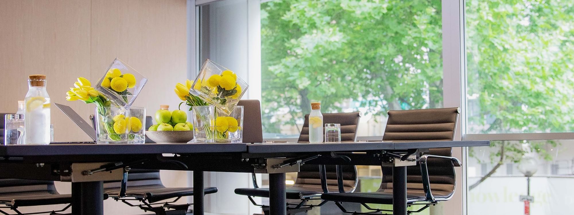 Lock In Your 2026 Events at 2025 Prices offer in a meeting room with flowers and fruit.